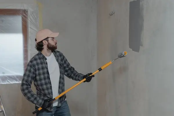 Painter rolling grey paint onto an interior wall in Topeka